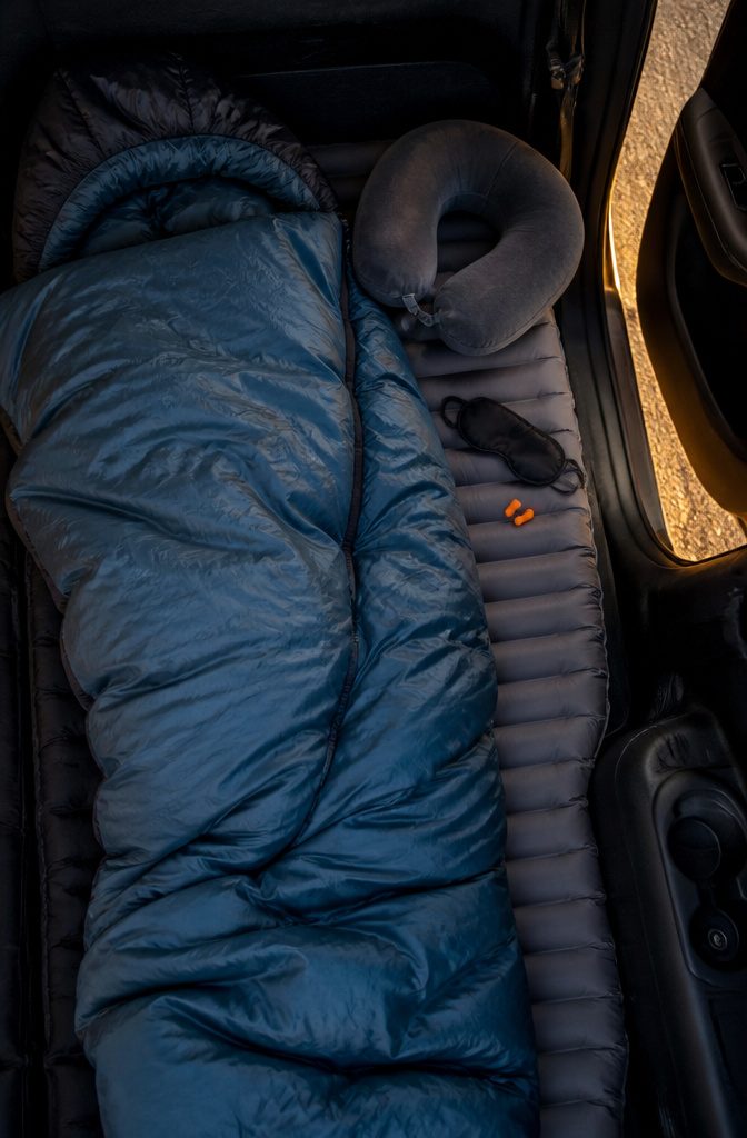 How to Sleep in a Car: Safety, Comfort and Gear for 2026 3 A sleeping bag and neck pillow arranged for sleeping in a car.