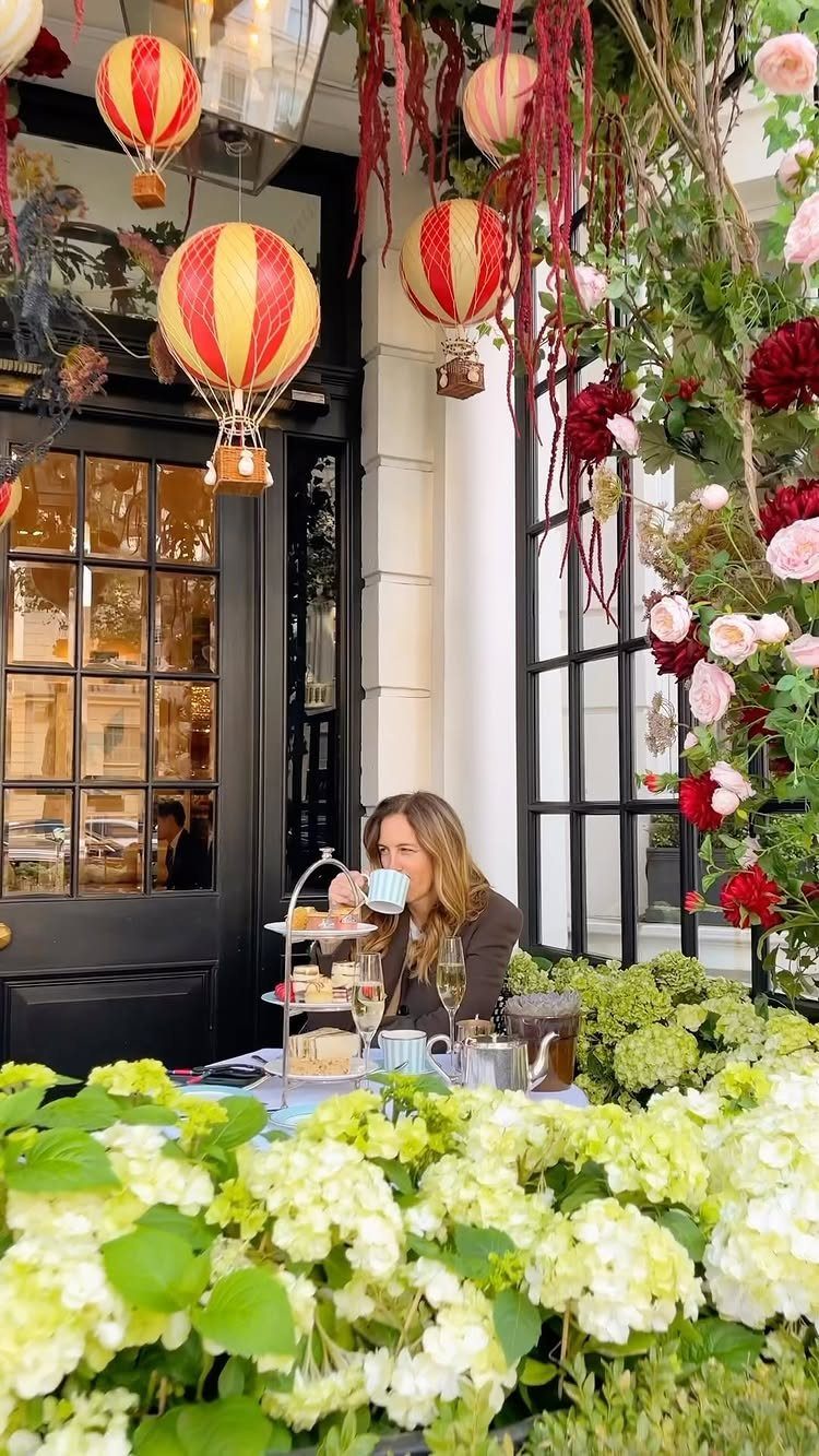 Woman enjoying afternoon tea with pastries and champagne in a floral garden setting