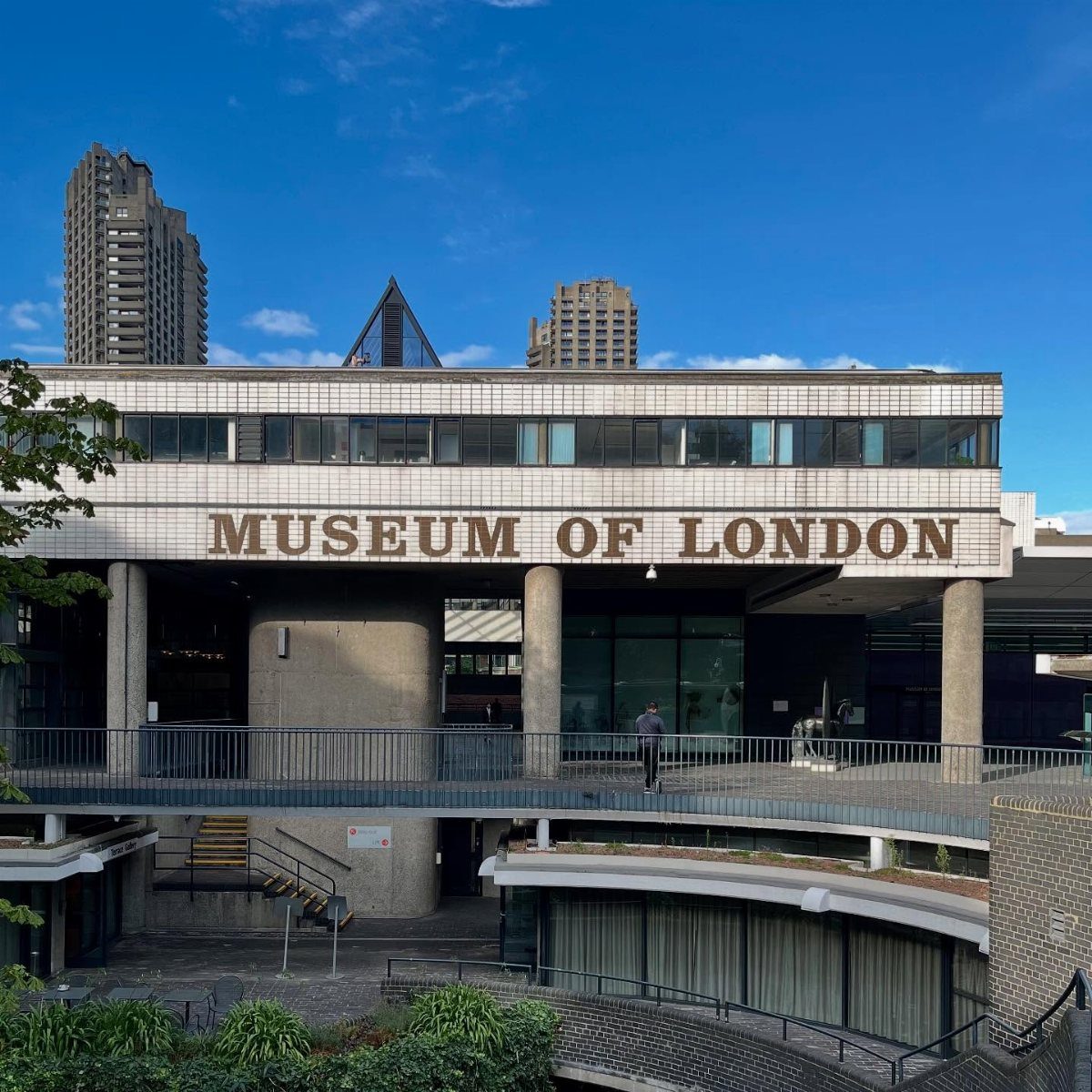 Museum of London building exterior with gold signage under a bright blue sky.