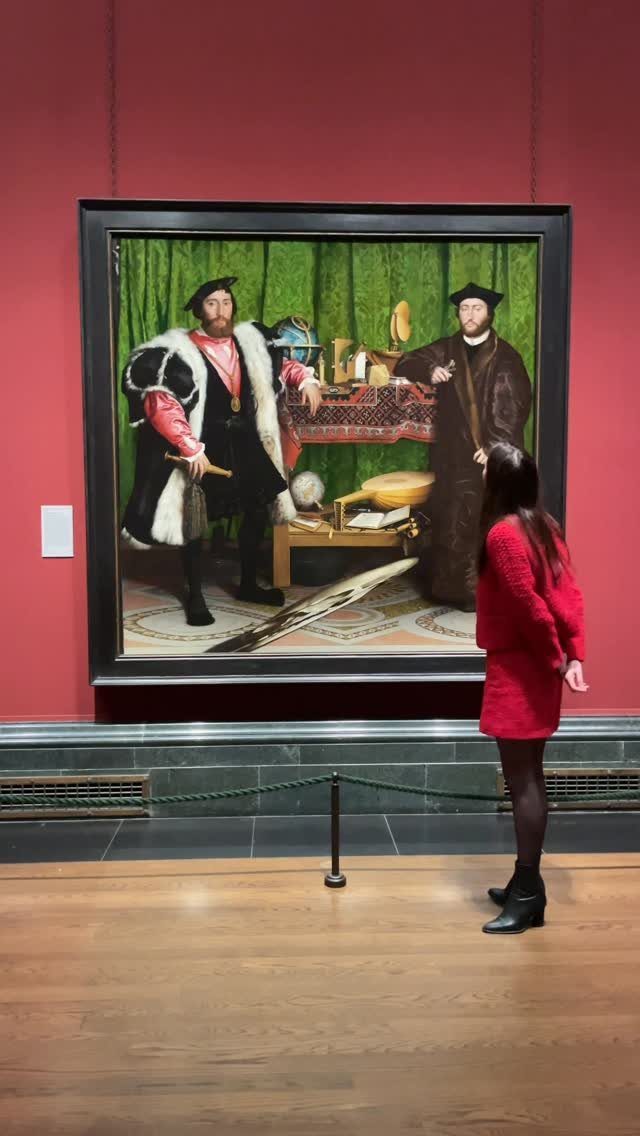 Woman in red dress viewing a large Renaissance painting in an art gallery