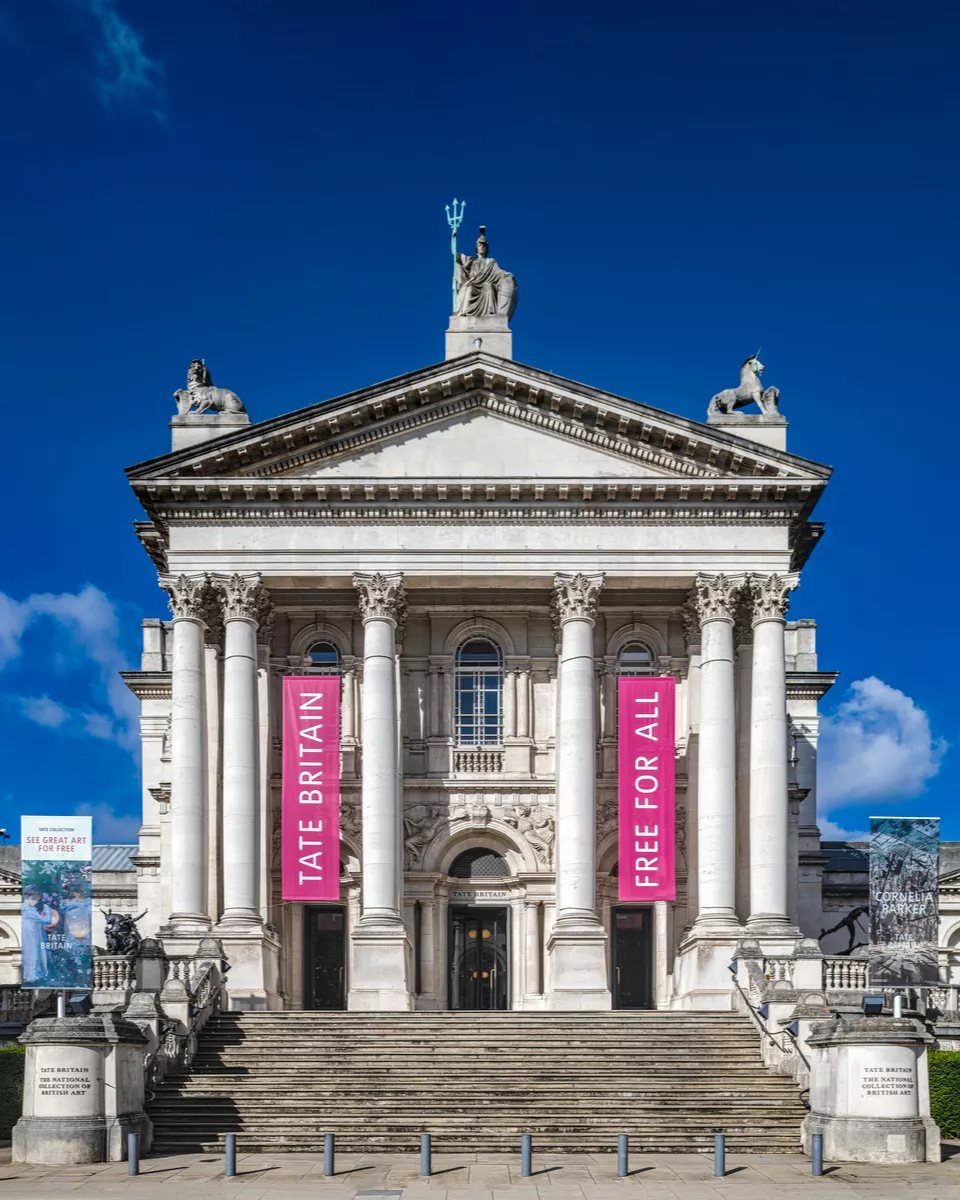 Tate Britain museum facade with white columns and pink banners under blue sky
