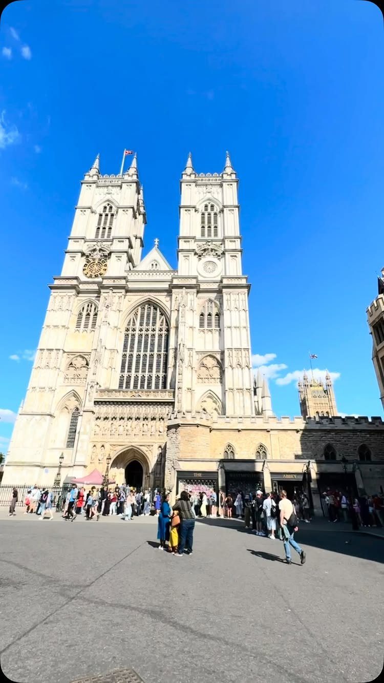 Westminster Abbey facade with twin towers and people gathered in the foreground plaza.