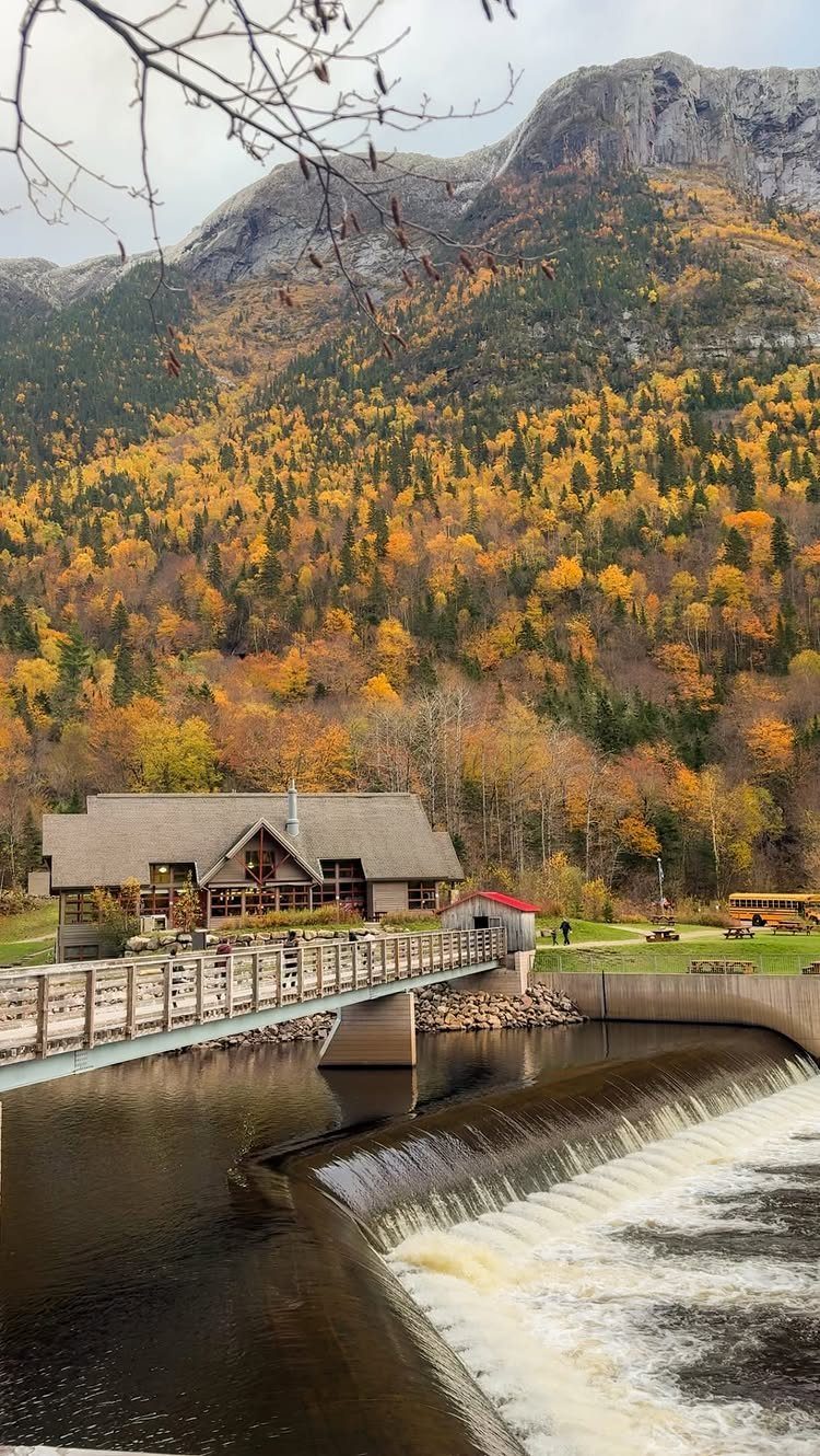 Wooden lodge and river dam set against autumn mountains with yellow foliage