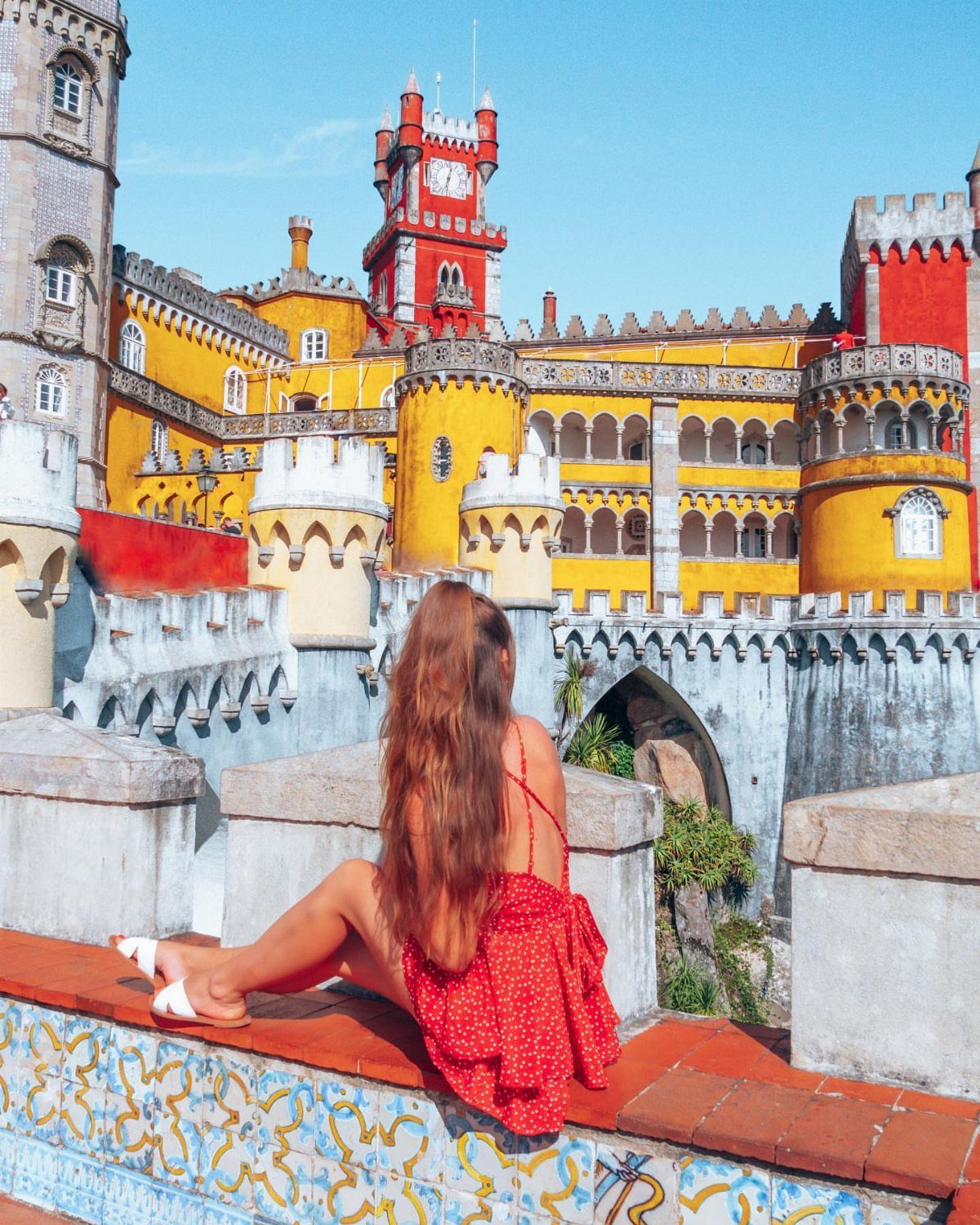 Woman in red dress looking at a colorful yellow and red castle