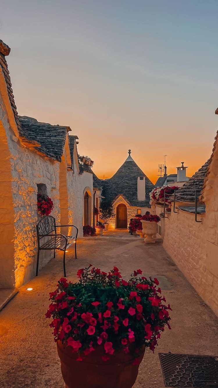 White trulli houses with conical roofs along a cobblestone street at sunset