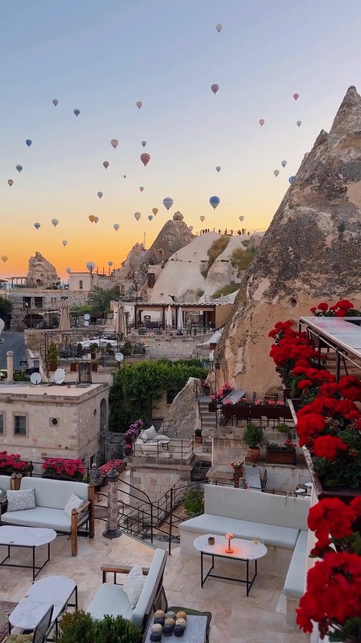 Cappadocia landscape with fairy chimneys, hot air balloons, and a flower-lined terrace.