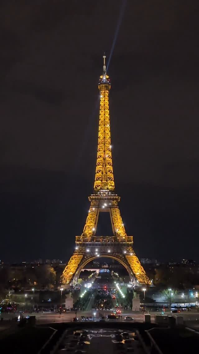 The Eiffel Tower glowing golden at night under a dark sky in Paris.