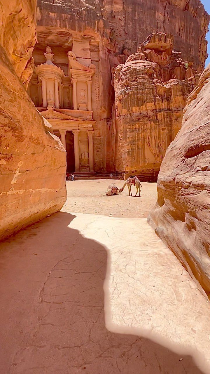 Al-Khazneh temple carved into red sandstone cliffs viewed through a narrow canyon passage