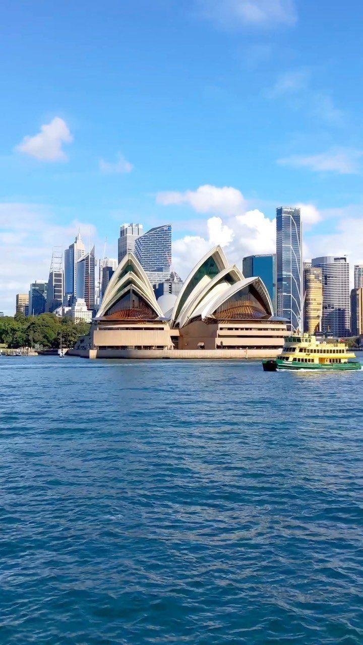 Sydney Opera House and city skyline across blue water under a sunny sky
