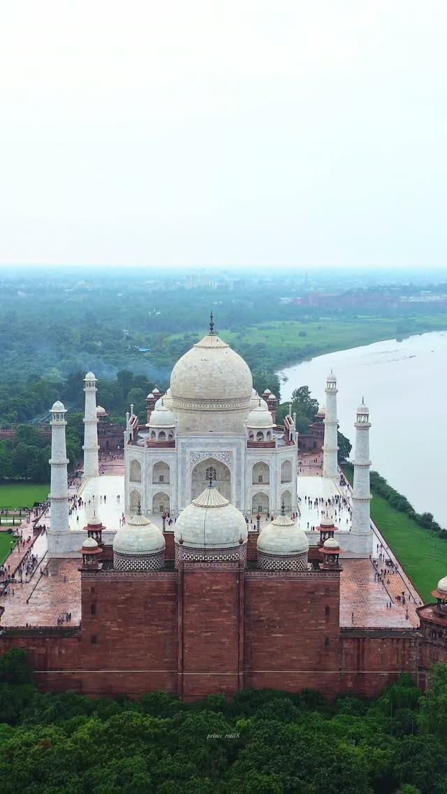 Taj Mahal white marble mausoleum with red sandstone foreground and river background