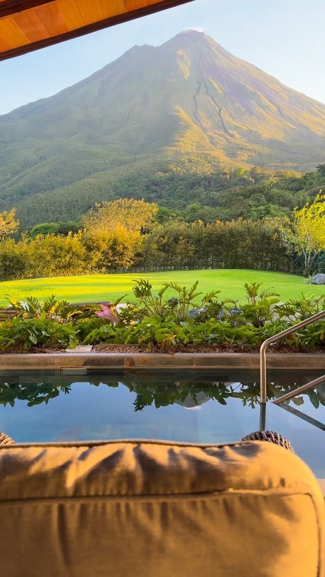 Conical volcano overlooking a lush green landscape and a luxury swimming pool.