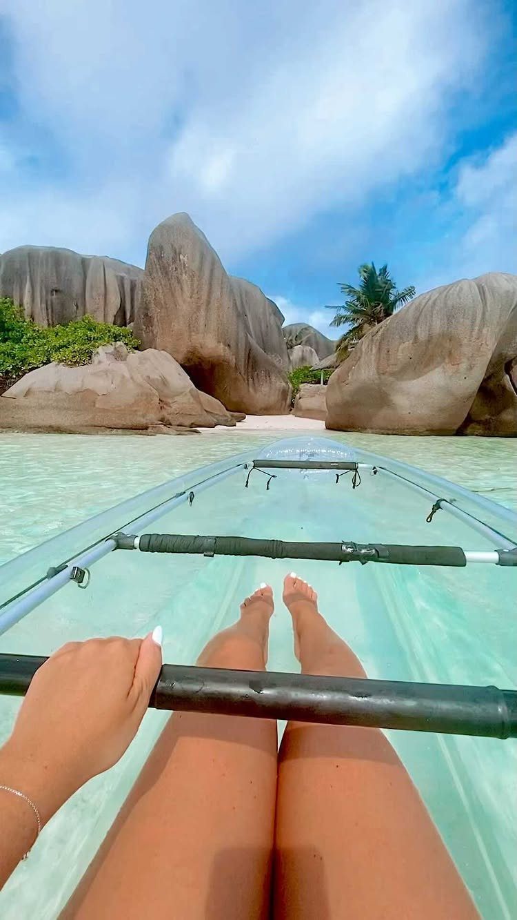 Clear kayak on turquoise water with large granite boulders and white sand beach.