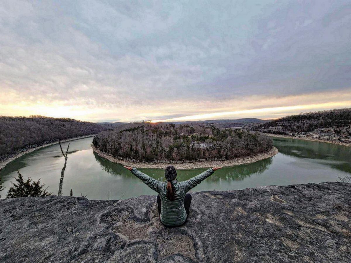 Nature Places to Visit: 19 Parks, Gardens and Overlooks 14 Person sitting on a rocky cliff overlooking a curving river and forest peninsula.