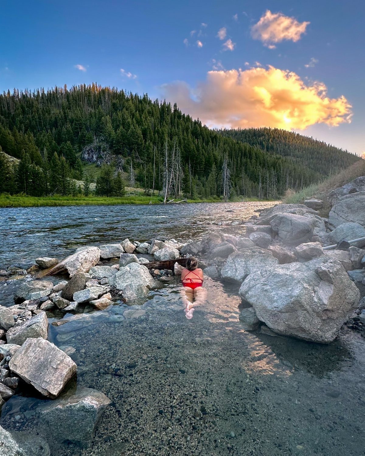 Nature Places to Visit: 19 Parks, Gardens and Overlooks 12 Person in red swimsuit soaking in a hot spring by a river and forest