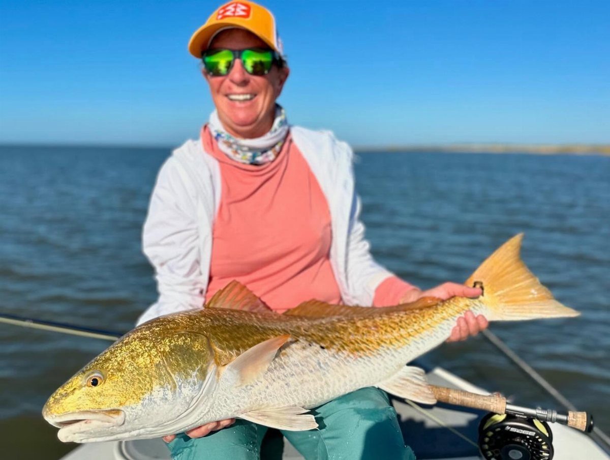 12 November Trip Ideas for Warm Beaches and Fall Color 8 Woman holding a large red drum fish while on a boat in open water