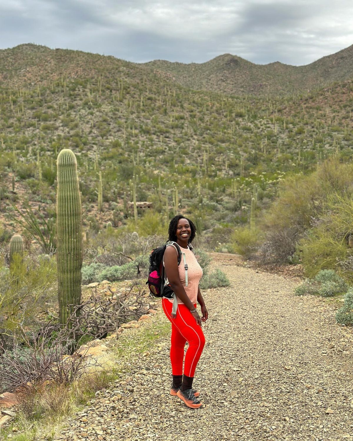 12 November Trip Ideas for Warm Beaches and Fall Color 9 Woman in red leggings standing on a desert path with saguaro cacti.