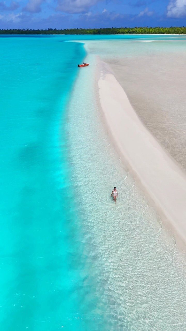 12 Places Like Bora Bora for Island Views and Lagoons 9 White sandbar curving through turquoise ocean water with a person walking nearby.