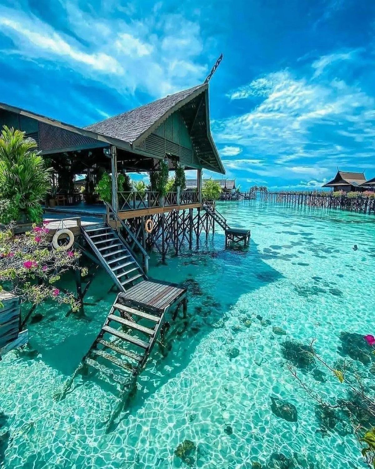 12 Places Like Bora Bora for Island Views and Lagoons 1 Wooden overwater villas with stairs descending into clear turquoise tropical ocean water.