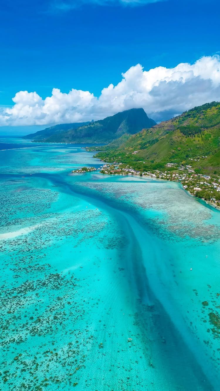 12 Places Like Bora Bora for Island Views and Lagoons 3 Lush green mountains with sharp peaks overlooking turquoise coral reefs and beaches.