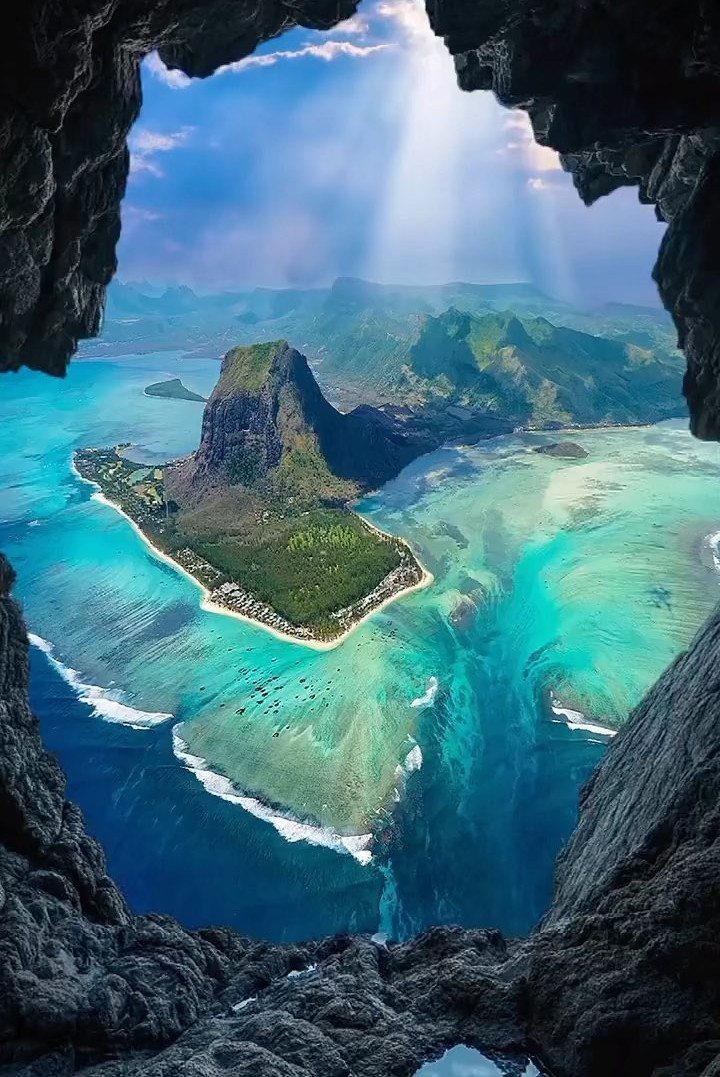 12 Places Like Bora Bora for Island Views and Lagoons 11 Tropical island with a volcanic peak and turquoise water seen through a cave opening.