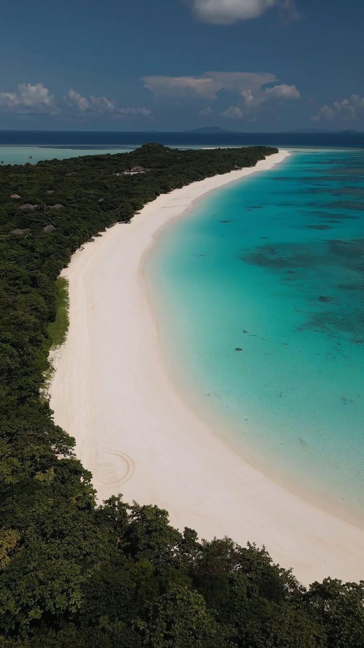 12 Places Like Bora Bora for Island Views and Lagoons 8 Curved white sand beach and turquoise water bordered by lush green tropical forest.