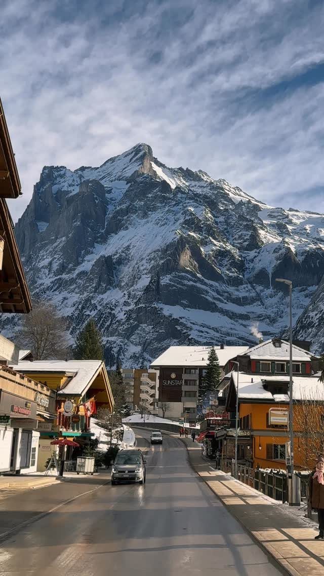 Snowy mountain peak overlooking a quiet alpine village street with traditional houses.