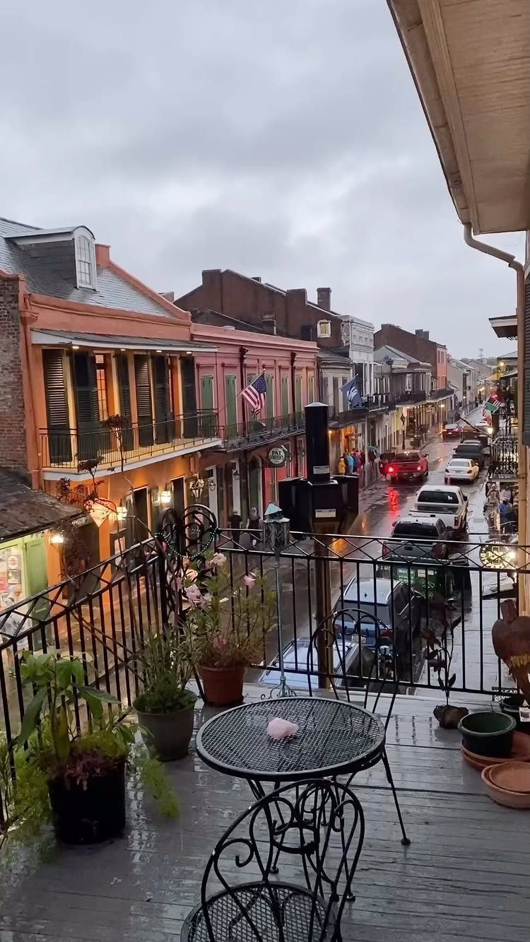 Rainy balcony view overlooking a street with colorful historic buildings and wrought-iron balconies.