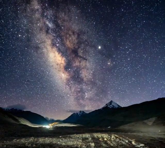 Milky Way galaxy stretching across a starry night sky over dark mountain peaks.