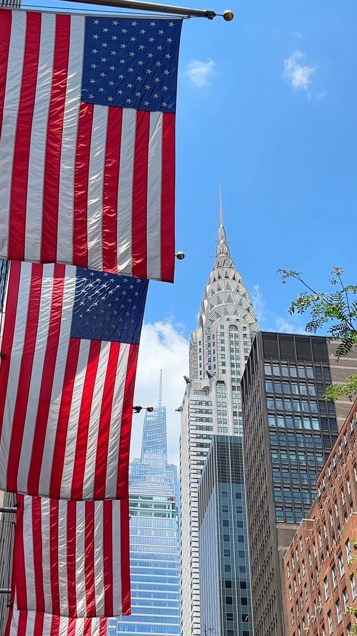 American flags hanging in front of the Chrysler Building and New York skyscrapers.
