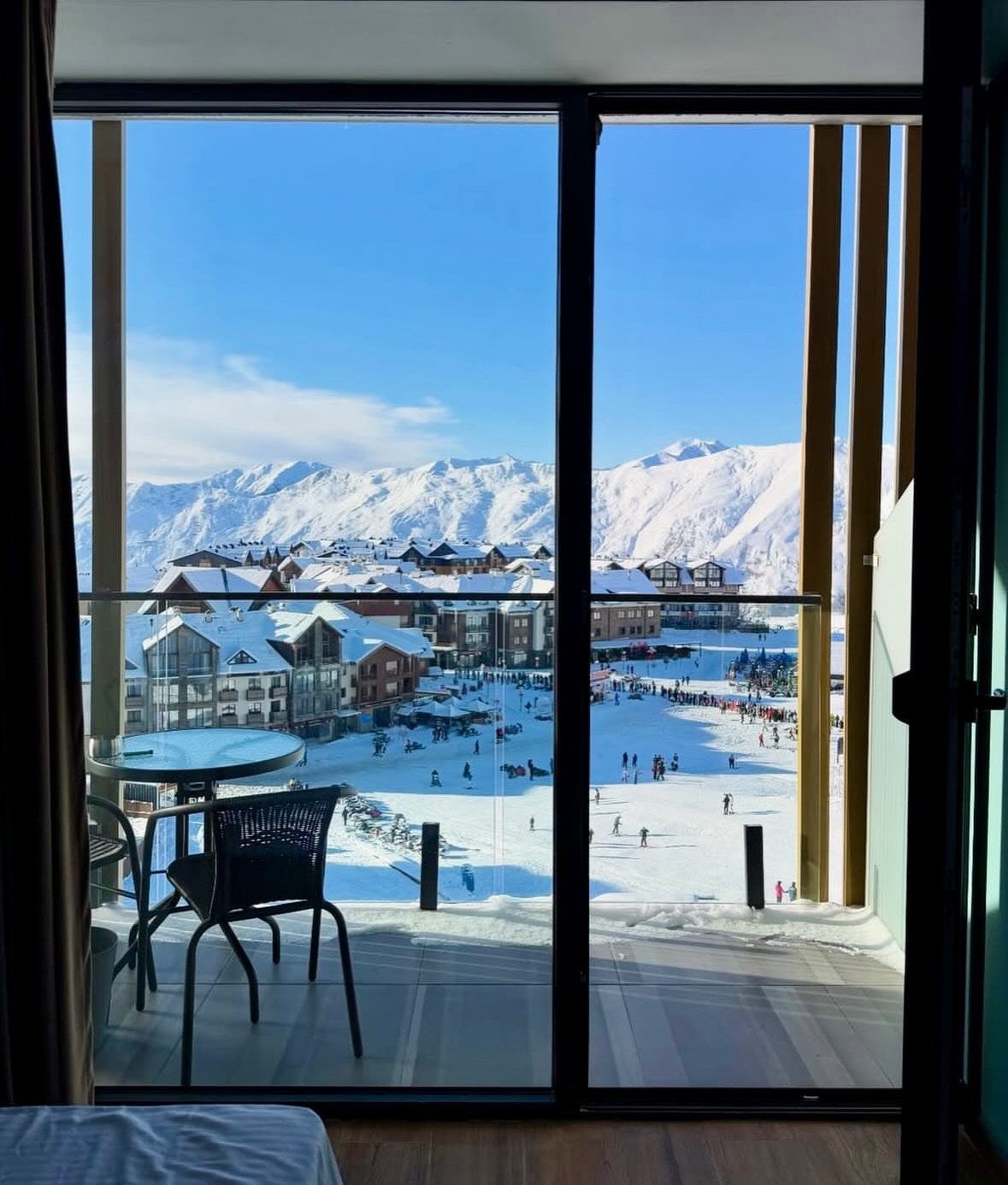 14 Places to Travel With Family: Beaches, Parks and Cities 14 Snowy mountain resort village viewed from a balcony with a table and chair.