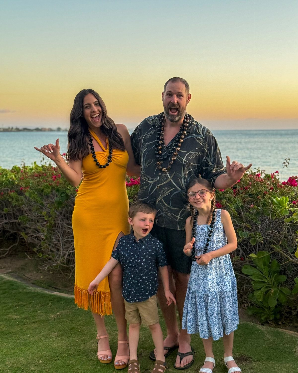 14 Places to Travel With Family: Beaches, Parks and Cities 6 Family of four wearing tropical attire and bead necklaces posing by a beach.