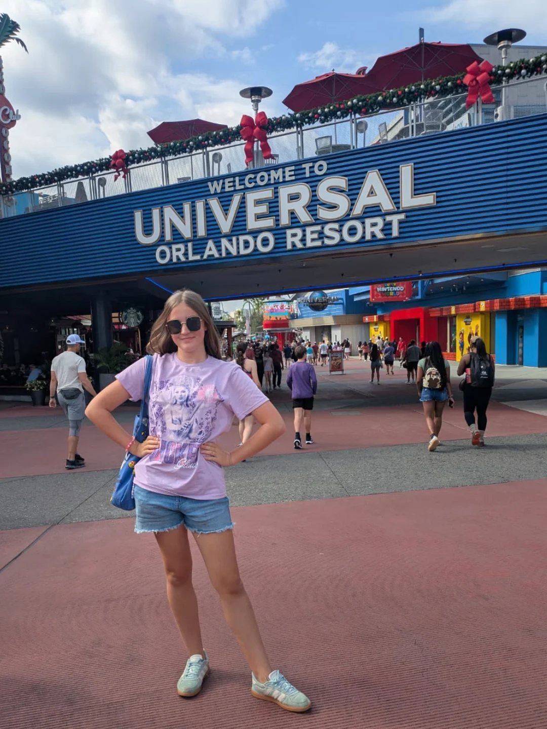 14 Places to Travel With Family: Beaches, Parks and Cities 2 Young woman posing in front of the Universal Orlando Resort entrance sign.