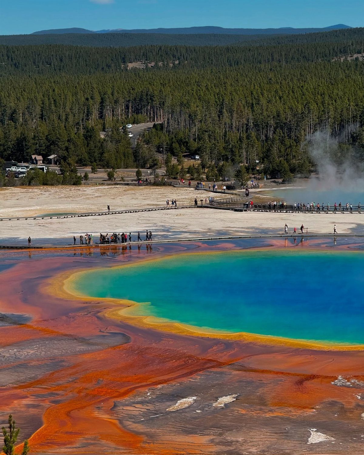 14 Places to Travel With Family: Beaches, Parks and Cities 4 Grand Prismatic Spring with colorful rings and tourists on a wooden boardwalk