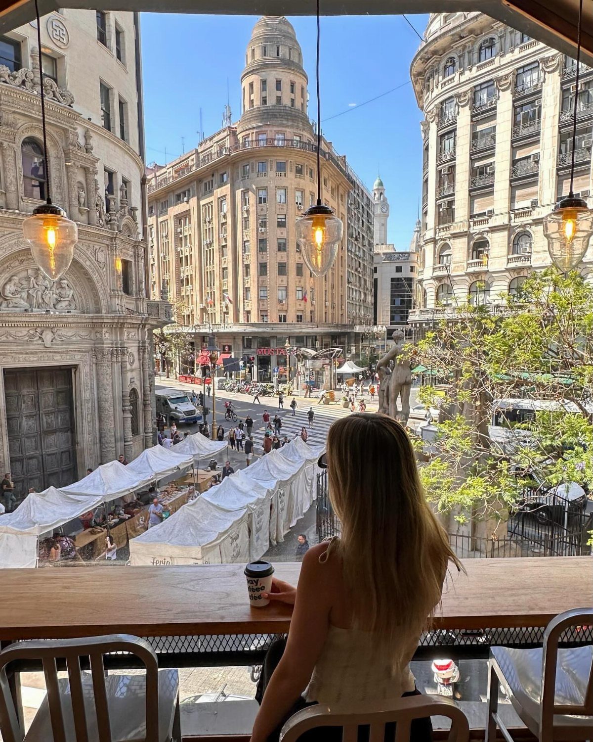 Places to Visit Around the World: 23 Ideas With Photos 5 Woman looking out over a city street with European architecture and market tents.