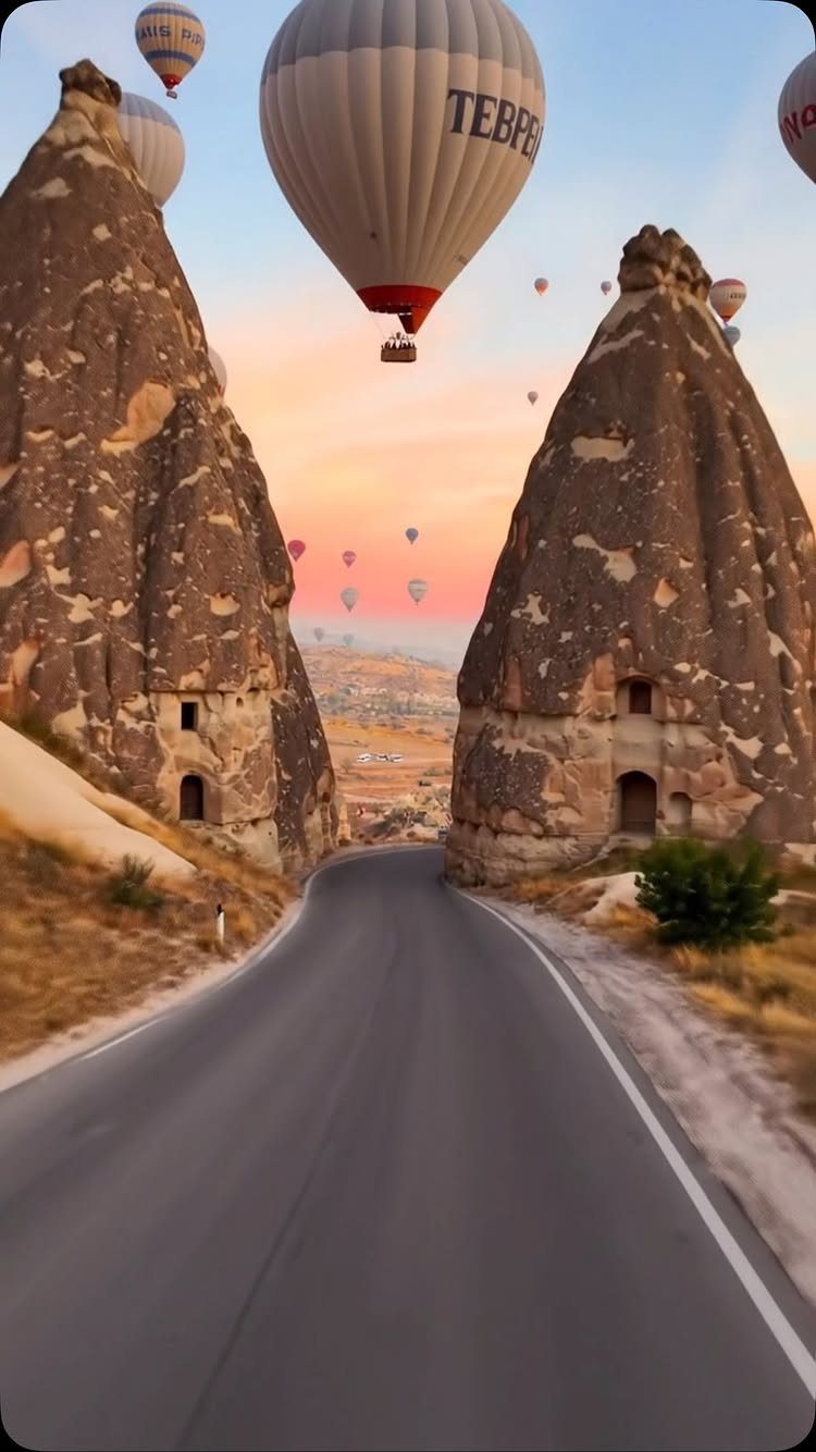 Places to Visit Around the World: 23 Ideas With Photos 10 Hot air balloons floating over a road and conical rock formations at dawn.