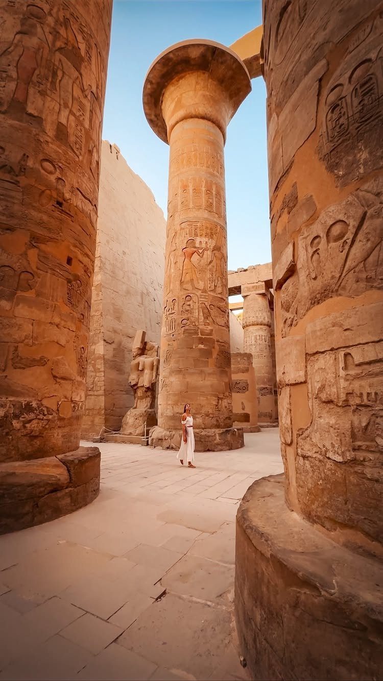 Places to Visit Around the World: 23 Ideas With Photos 17 Woman in white dress standing among massive carved sandstone columns in Egypt