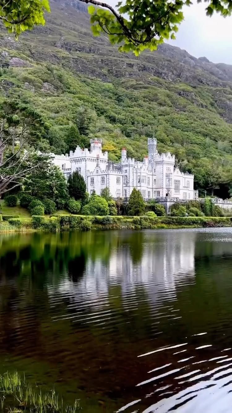 Places to Visit Around the World: 23 Ideas With Photos 22 White castle with turrets reflecting in a lake against a green mountain backdrop
