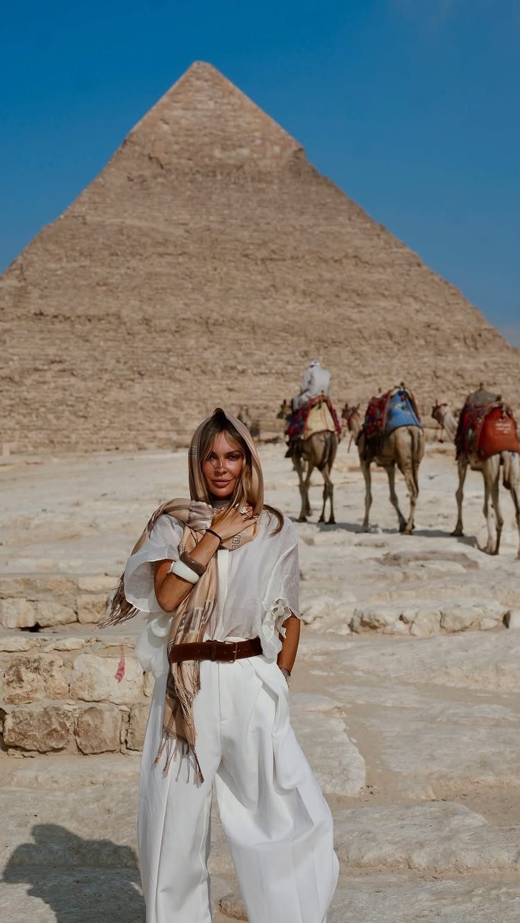 Places to Visit Around the World: 23 Ideas With Photos 1 Woman in white standing before a large Egyptian pyramid and camels in the desert