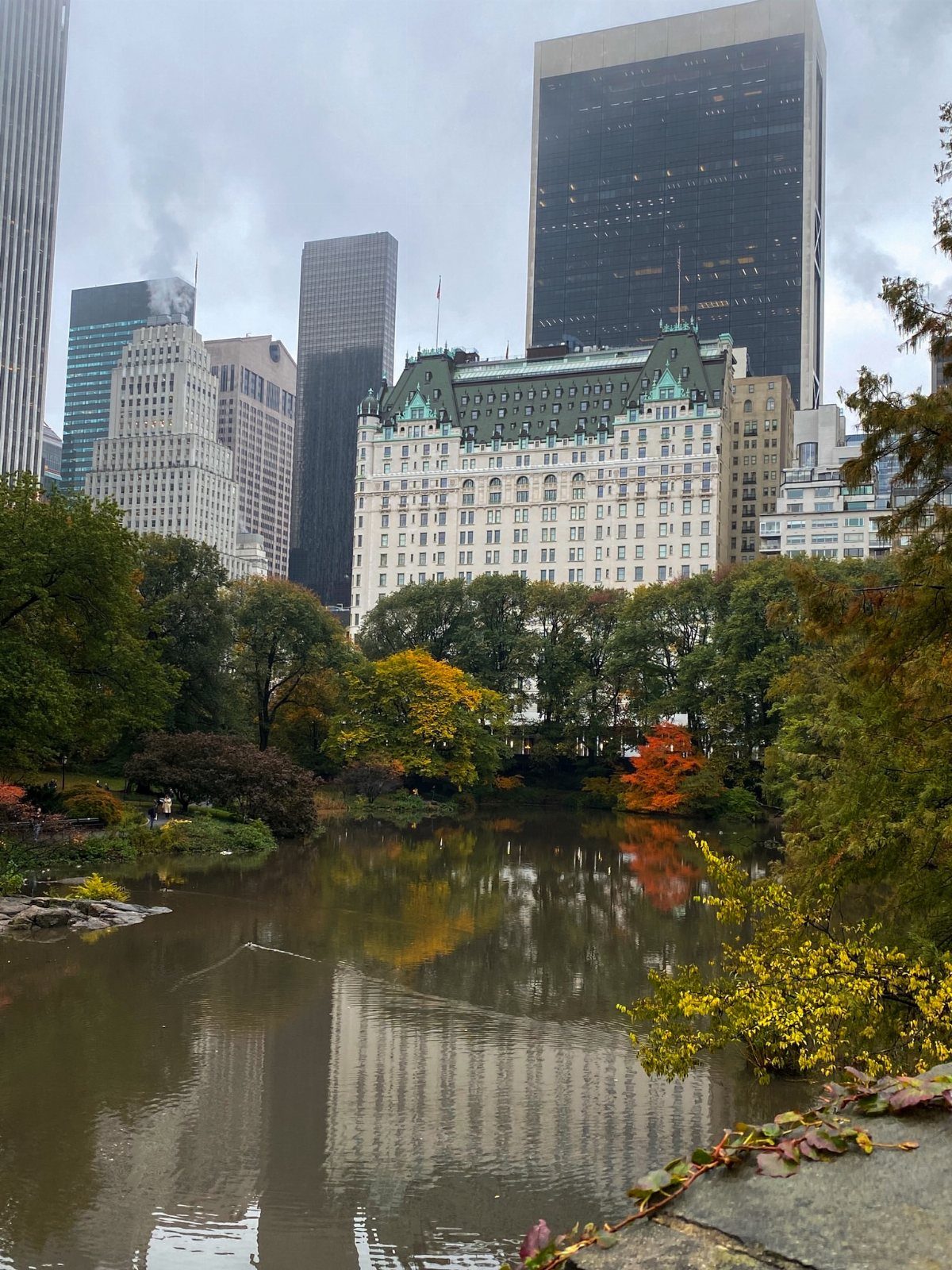 Prettiest Place to Visit: 21 Ideas Around the World 16 City pond reflecting skyscrapers and autumn foliage in a lush urban park.