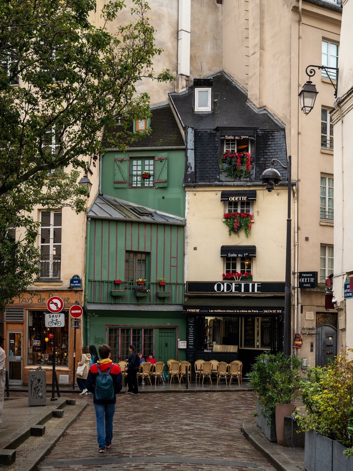 Prettiest Place to Visit: 21 Ideas Around the World 20 Cobblestone street with colorful historic buildings and a person walking in Paris.