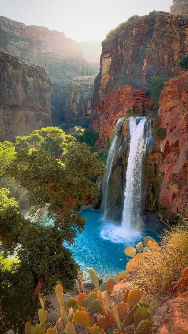 Prettiest Place to Visit: 21 Ideas Around the World 14 Waterfall cascading into a blue pool surrounded by red rock canyon cliffs.