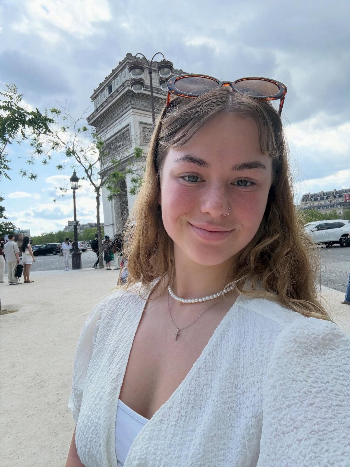 13 Pretty Countries to Visit for Coasts, Peaks and Ruins 10 Young woman smiling in front of the Arc de Triomphe in Paris, France.