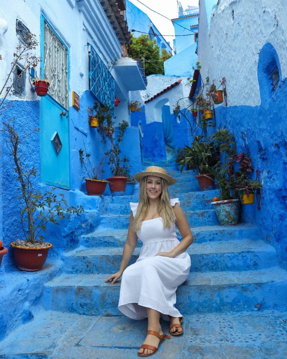 13 Pretty Countries to Visit for Coasts, Peaks and Ruins 11 Woman in white dress sitting on blue steps in a Moroccan blue city alley