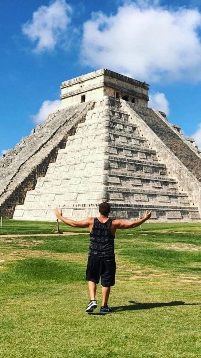 26 Pretty Places Around the World, From Fjords to Falls 16 Man with arms open facing the El Castillo pyramid at Chichen Itza