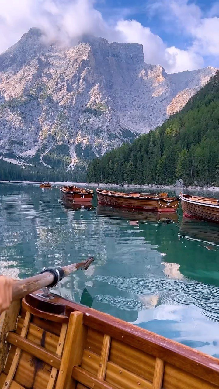 26 Pretty Places Around the World, From Fjords to Falls 26 Wooden rowboats on a turquoise lake with jagged mountains and pine forests.