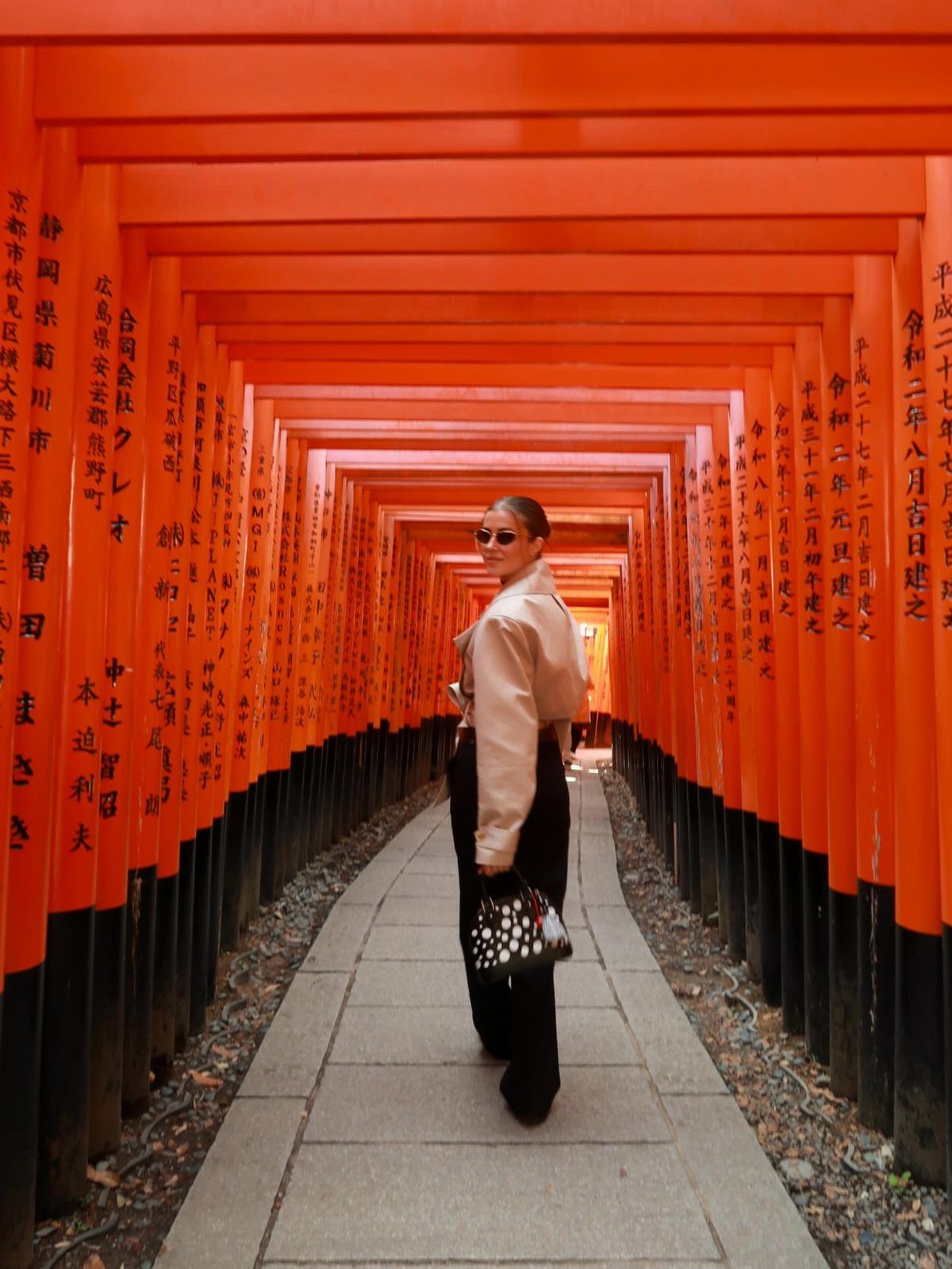 26 Pretty Places Around the World, From Fjords to Falls 23 Woman walking through a tunnel of vermillion torii gates at Fushimi-Inari Taisha Shrine.