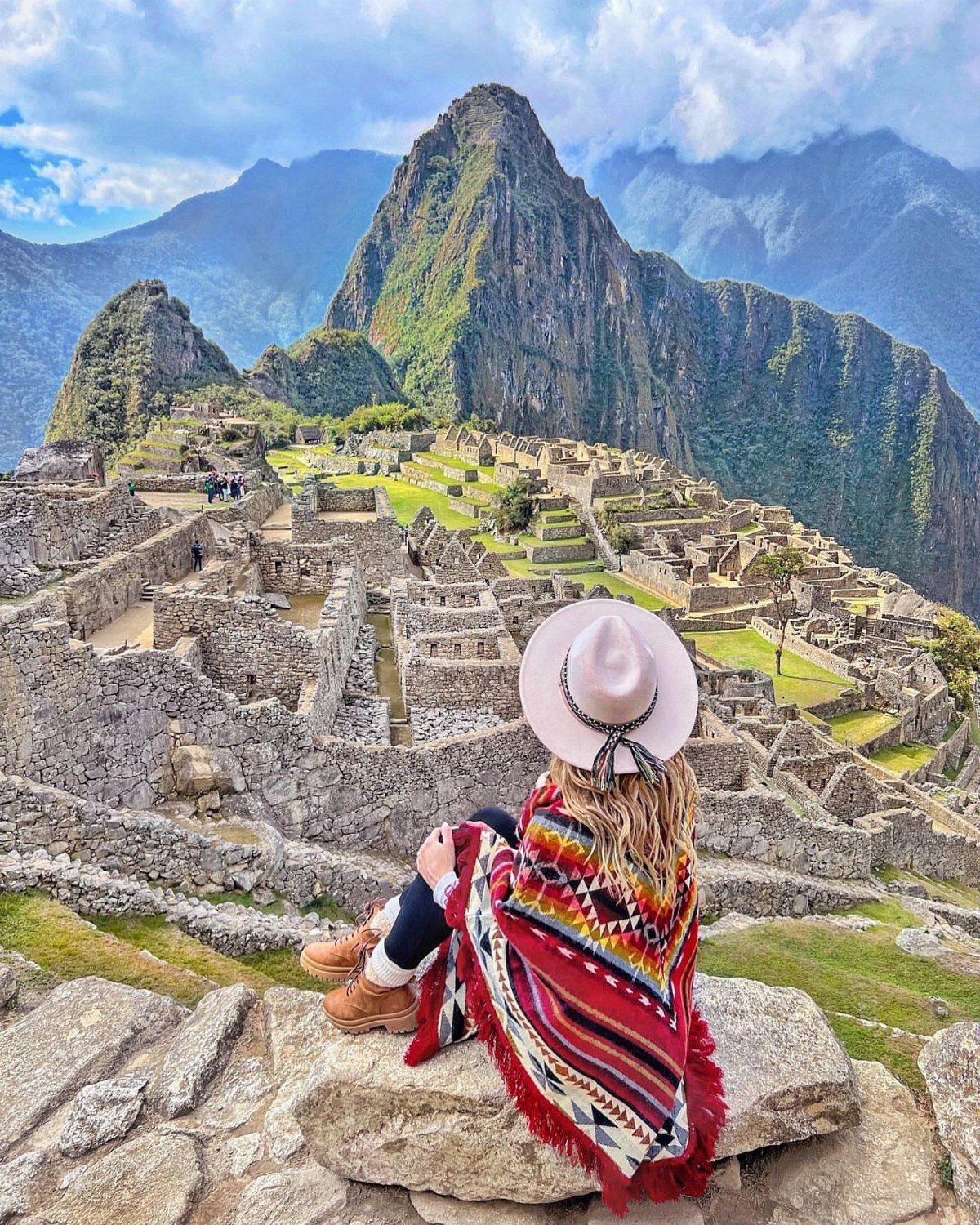 26 Pretty Places Around the World, From Fjords to Falls 3 Woman in a colorful poncho overlooking the ancient stone ruins of Machu Picchu.