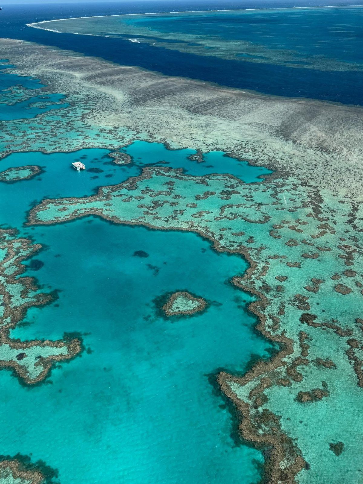 14 Pretty Places in Australia, from Reefs to Wine Regions 1 Aerial view of turquoise lagoons and coral reefs in a deep blue ocean.