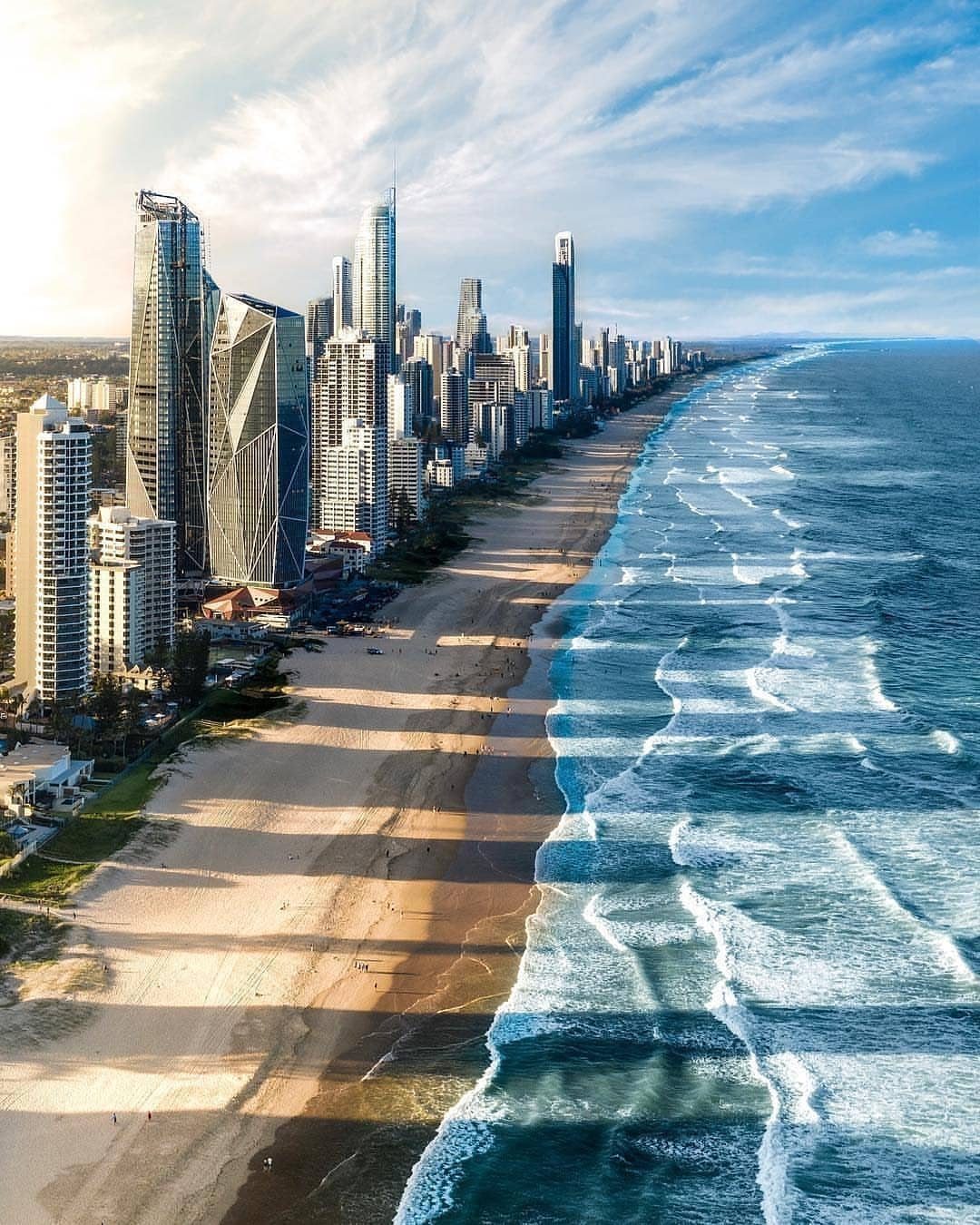 14 Pretty Places in Australia, from Reefs to Wine Regions 9 Coastal skyline with tall skyscrapers bordering a long sandy beach and blue ocean.