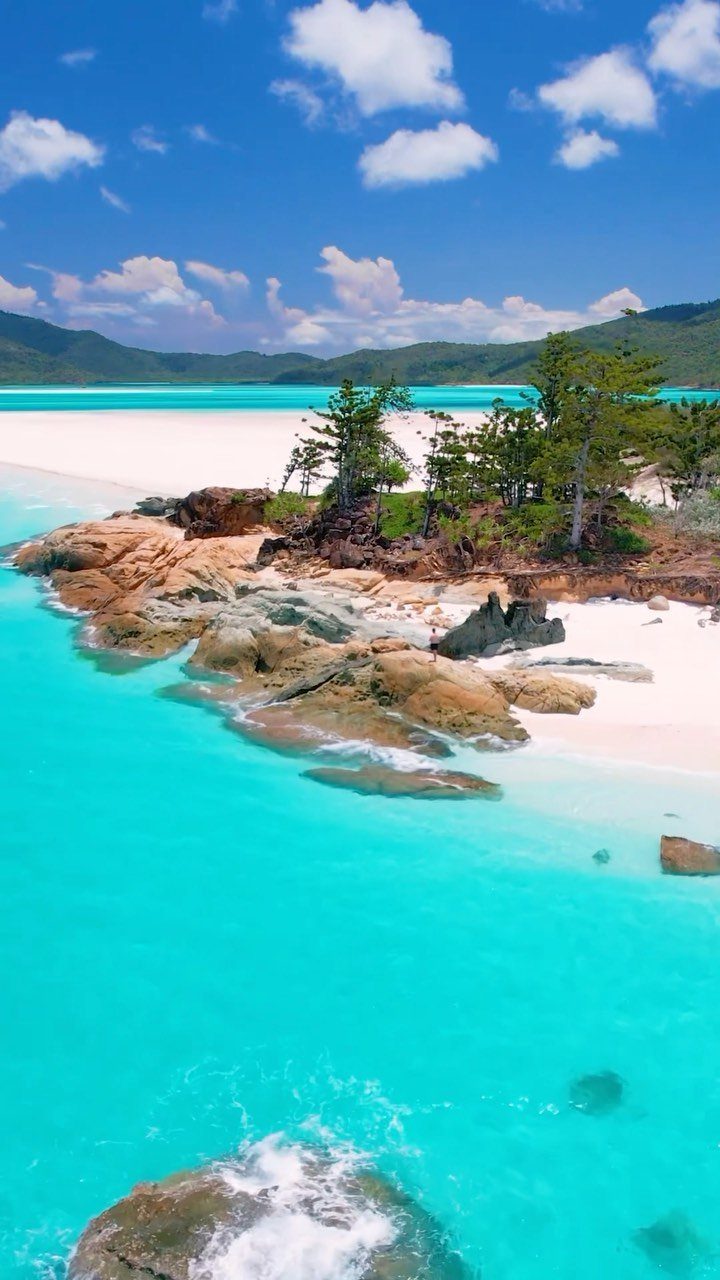 14 Pretty Places in Australia, from Reefs to Wine Regions 5 White sand beach and turquoise water with rocky outcrops and green trees.